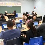 A classroom of kids using laptops and online live classes